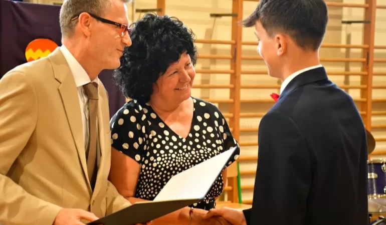 Wójt i przewodniczący Rady Gminy wręcza nagrodę uczniowi